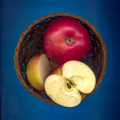 Fresh ripe red apples in a basket on a blue background. Top view.
