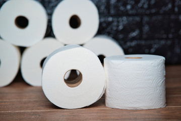 Muchos rollos de papel higiénico de baño desechable de color blanco sobre una tabla de madera marrón