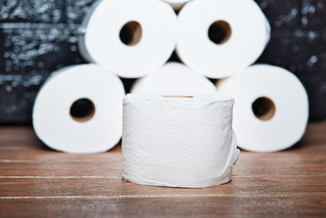 Muchos rollos de papel higiénico de baño desechable de color blanco sobre una tabla de madera marrón
