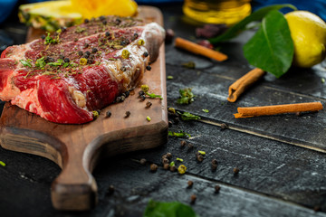 Raw meat on a wooden board with herbs and spices,lemon and cinnamon sticks