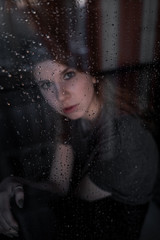 portrait of a girl through a wet window