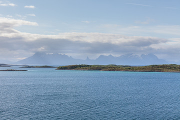 A mystical fjord in Norway with mountains and fog hanging over the water in polar day. midnight sun, selective focus