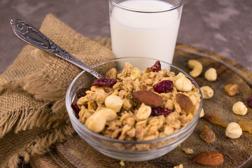 
Granola with nuts and berries and a glass of milk on a wooden board. The concept of healthy and tasty breakfasts. Close-up.