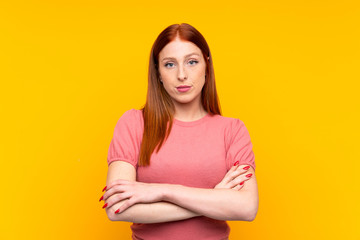 Obraz premium Young redhead woman over isolated yellow background keeping arms crossed