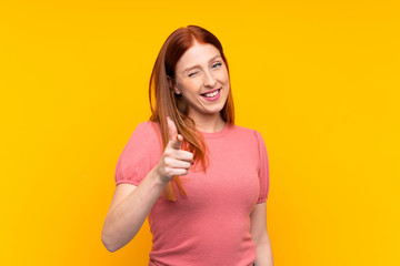 Fototapeta na wymiar Young redhead woman over isolated yellow background points finger at you