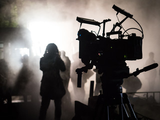 Silhouette of a professional movie camera in the dark on the set.