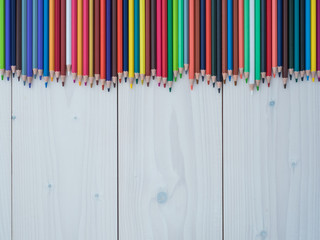 Set of colored pencils arranged in a row on wooden background