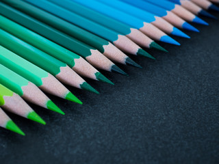 Set of colored pencils arranged in a row on slate background