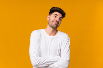 Young man over isolated orange background making doubts gesture while lifting the shoulders