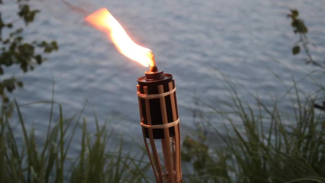 The torch was made by speleologists before going to the cave as in the old days. Homemade torch on the background of a pond
