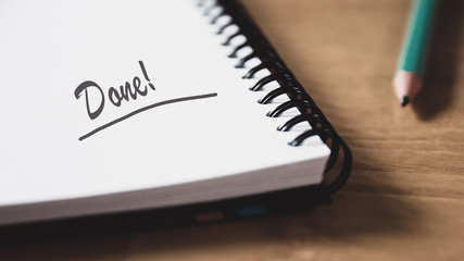 Front view of pencil and open notebook with handwritten text Done. 