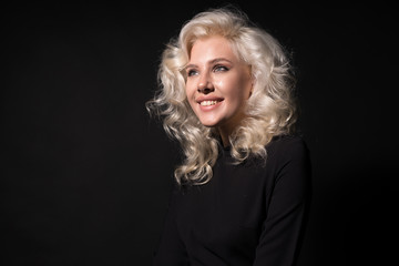Happy blonde curly woman smiling isolated on black background