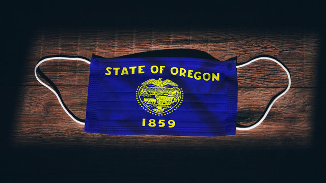 Oregon Flag. Coronavirus Covid 19 In U.S. State. Medical Mask Isolate On A Black Background. Face And Mouth Masks For Protection Against Airborne Infections In USA, America