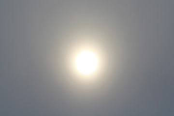 The sun in the haze against the blue sky. Defocused background for design.
