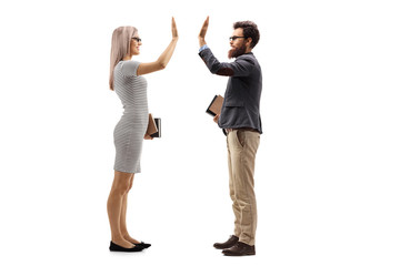 Blond young woman holding books and gesturing high-five with a bearded man