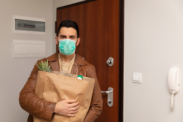 Fototapeta na wymiar A man in a protective medical mask returned home from a grocery store.