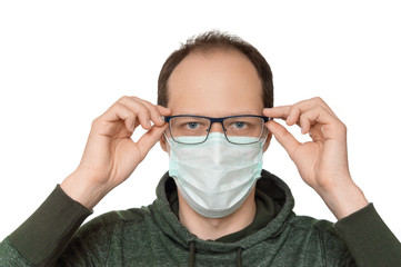 Young man with glasses wearing protective mask. Isolated on white background, green hoodie.