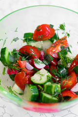 Fresh vegetable salad close-up. Cucumber, radish, tomatoes, chives, ukrom. Vegetable salad seasoned with olive oil.
