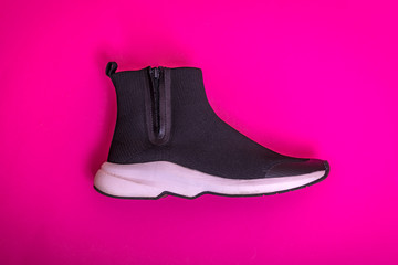 Beautiful fashionable socks sneakers on a pink background. Minimal design of . Stylish black sneakers. Training time concept.