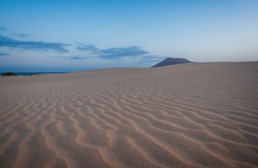 Ripples on sand dune near Corralejo with volcano mountains in the background, Fuerteventura, Canary Islands, Spain. October 2019