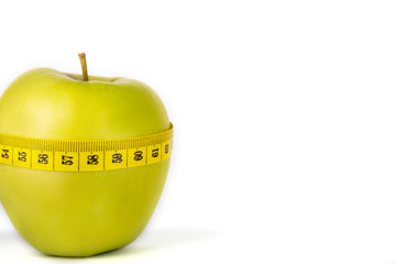 Proper nutrition. Measuring tape  and green apple on a white isolated background. Achieving the goal of losing weight and diet.