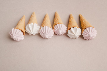 Small crispy waffle ice cream cups with colored marshmallows on a pastel background