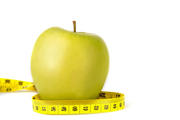 Proper nutrition. Measuring tape  and green apple on a white isolated background. Achieving the goal of losing weight and diet.