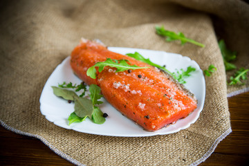 piece of salty red fish with different seasonings and herbs in a plate