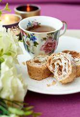 cup of tea and puff pastry roll with apple and raisins