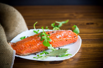 piece of salty red fish with different seasonings and herbs in a plate