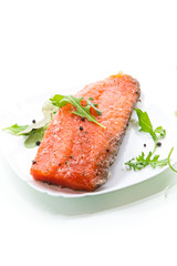 piece of salty red fish with different seasonings and herbs in a plate