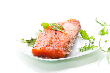 piece of salty red fish with different seasonings and herbs in a plate