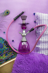 purple hookah with pillows and national fabric out of focus with soft blurring on a purple background with the effect of grain