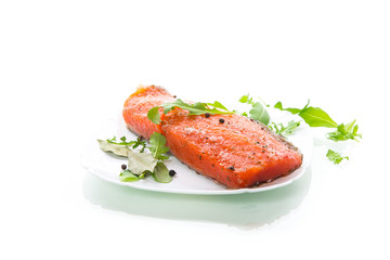 piece of salty red fish with different seasonings and herbs in a plate