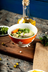 Broth soup with herbs,potato and carrot in a red bowl served with olive oil