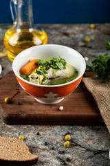 Broth soup with herbs,potato and carrot in a red bowl