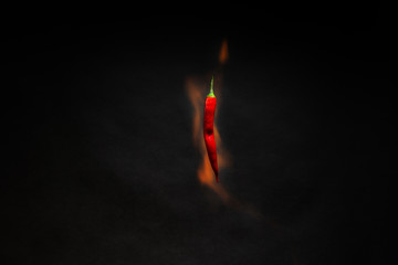 Red hot chili peppers on fire on an isolated black background. The concept of levitation