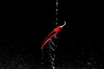 Red hot chili pepper flies in drops of water. Levitation