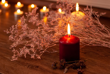 Aromatherapy flame closeup picture. Beautyful burning light wine red candles with wooden background and dry flowers