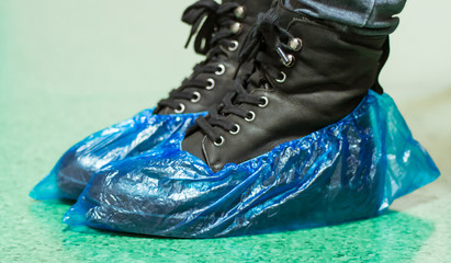 Blue medical shoe covers are worn over shoes on the floor, hygiene and cleanliness in medical institutions. Selective focus	
