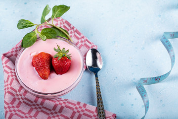 A bowl of pudding with strawberry aroma with fruits on it, isolated on blue on a red towel