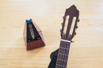Guitar and musical metronome on wooden background