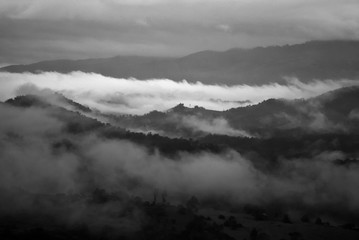 View landscape with silhouettes of mountains range with mist or covered by heavy fog