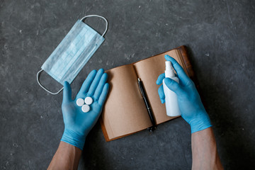 The concept of working from home in the coronavirus pandemic. Protection from covid-19 face mask antiseptic and tablet notepad on a gray background 