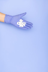 Hands in blue medical gloves hold handful white pills on light blue background. Minimal medical concept. Flat lay, top view, copy space