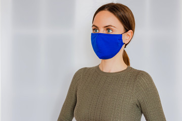 A young caucasian woman with light brown hair in a cotton blue medical face mask