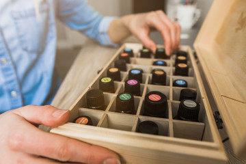 Young woman's hands choosing an essential oil from her essential oil storage box - obrazy, fototapety, plakaty