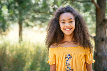Portrait of smiling curly haired girl outside in nature