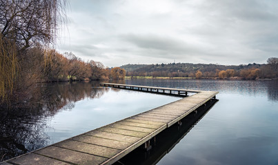 Lonely footbridge on a cloudy morning at Max-Eyth-See in Stuttgart; calm, smooth