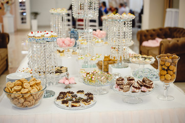 Beautifully decorated sweet buffet table on which cakes, muffins, marshmallows, pecans.  Dessert table for a party, goodies for the wedding. Close up. Candy bar. A buffet for a wedding